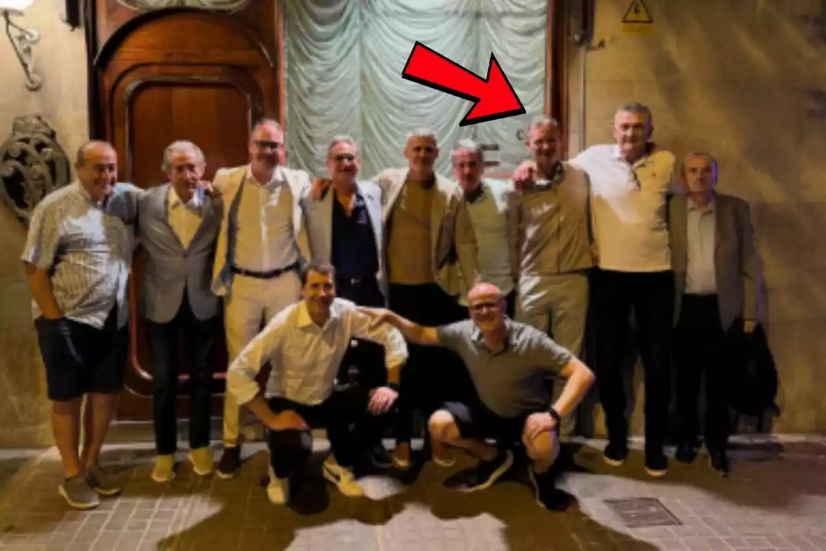 A group of men posing together on the street in front of a wooden door, next to a restaurant in Barcelona, with a red arrow pointing to one of them, who is Iñaki Urdangarin. A group of men posing together on the street in front of a wooden door, next to a restaurant in Barcelona, with a red arrow pointing to one of them, who is Iñaki Urdangarin.