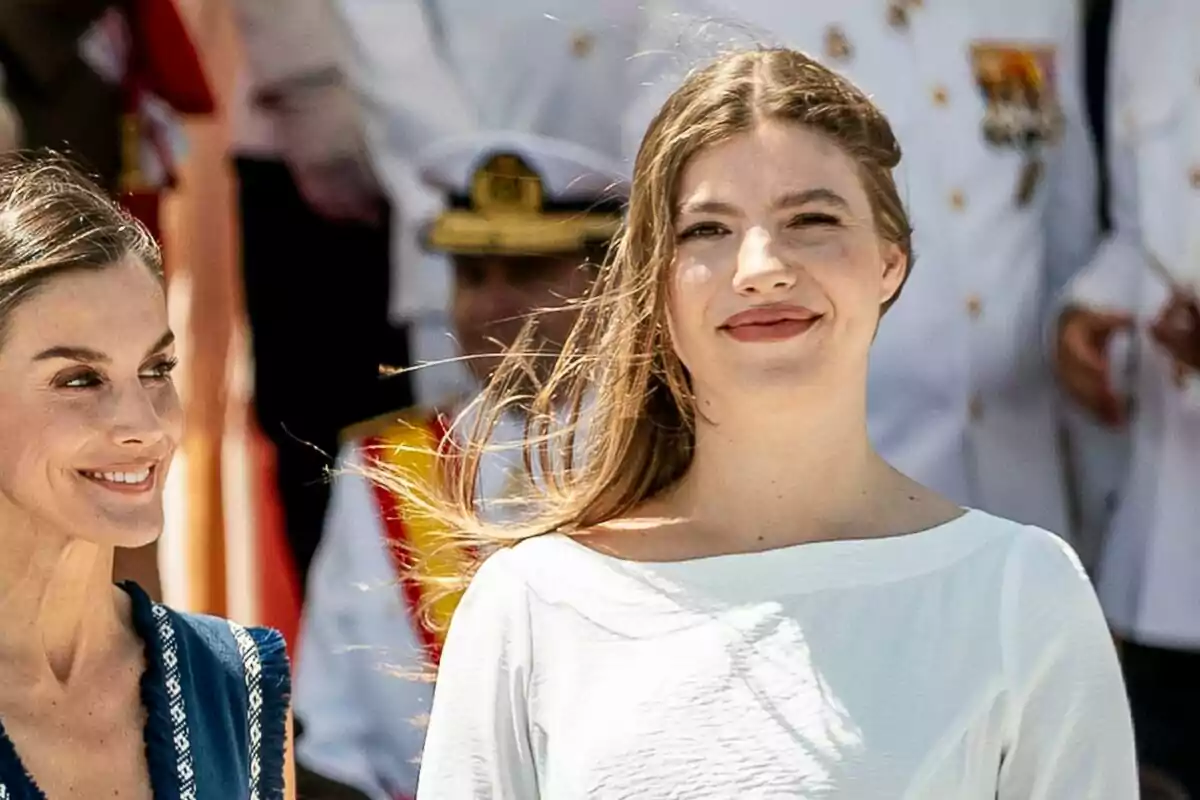 La reina Letizia i la infanta Sofía somriuen a l’aire lliure durant un esdeveniment formal amb persones uniformades al fons La reina Letizia i la infanta Sofía somriuen a l’aire lliure durant un esdeveniment formal amb persones uniformades al fons