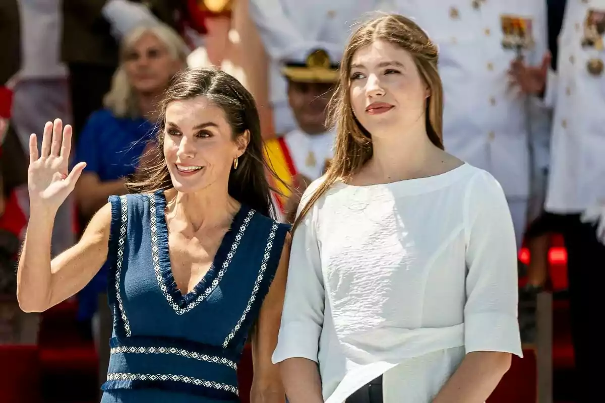 La reina Letizia i la infanta Sofía somriuen en un esdeveniment a l’aire lliure, una d’elles saluda amb la mà mentre l’altra mira cap endavant, totes dues envoltades de persones vestides amb uniforme blanc al fons. La reina Letizia i la infanta Sofía somriuen en un esdeveniment a l’aire lliure, una d’elles saluda amb la mà mentre l’altra mira cap endavant, totes dues envoltades de persones vestides amb uniforme blanc al fons.