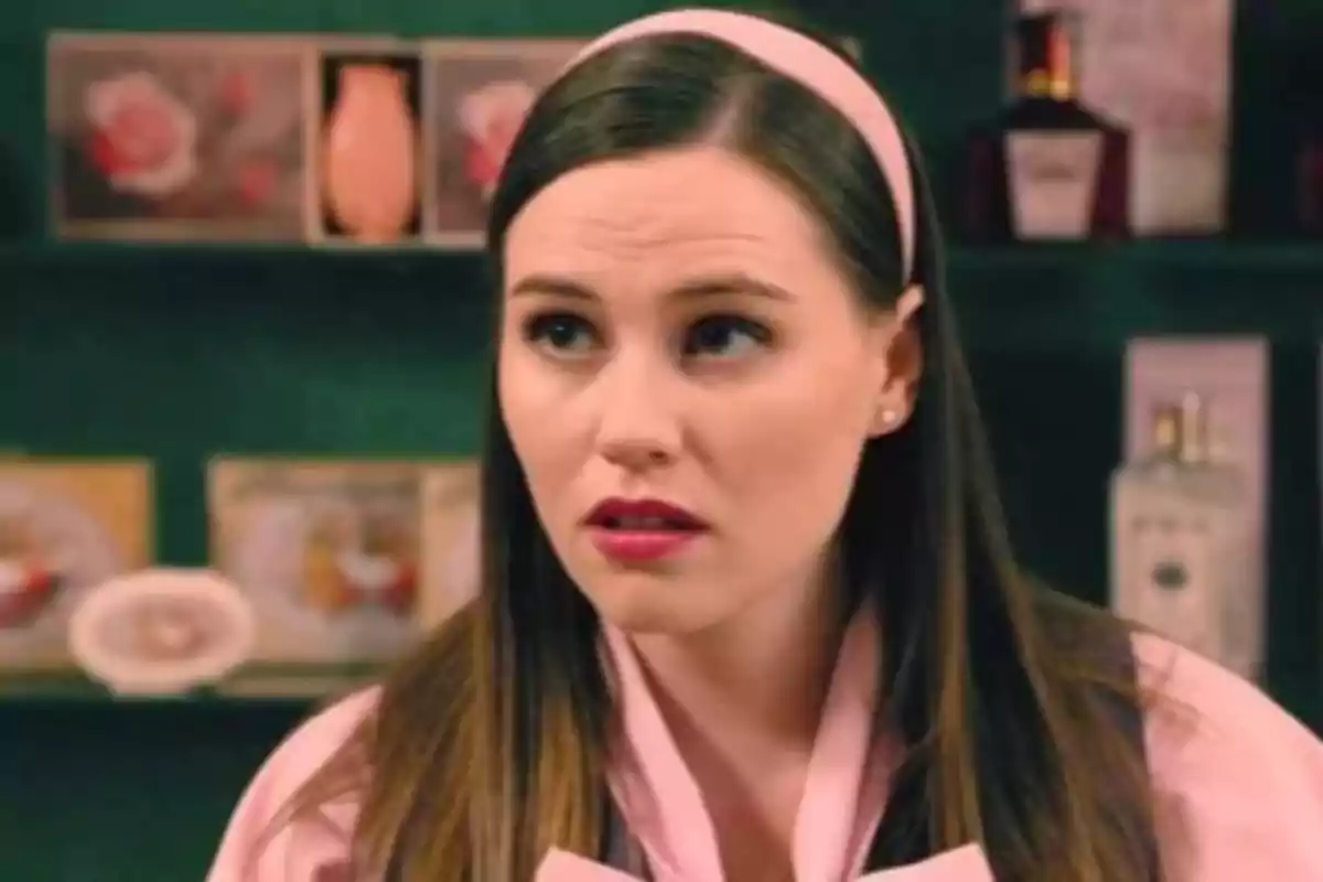Dona jove amb diadema rosa i bata rosa en una botiga de perfums i cosmètics Dona jove amb diadema rosa i bata rosa en una botiga de perfums i cosmètics