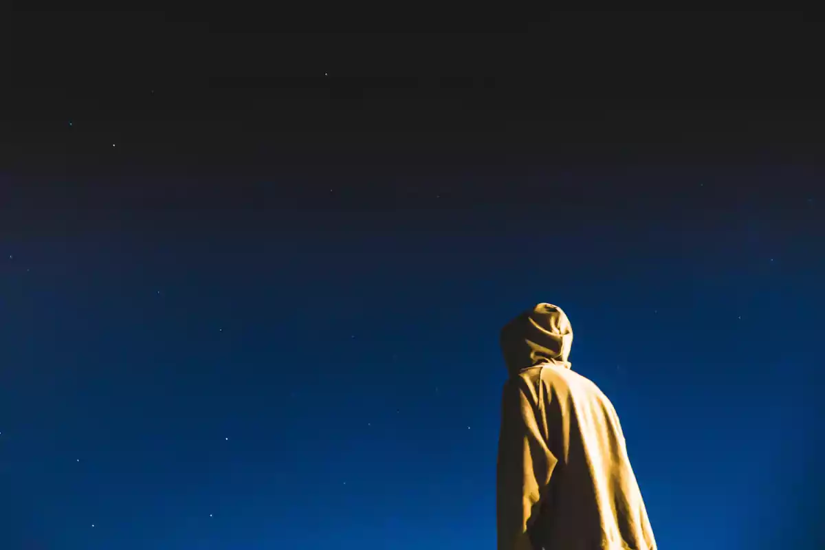 Person wearing a hoodie looking at the starry sky at night Person wearing a hoodie looking at the starry sky at night