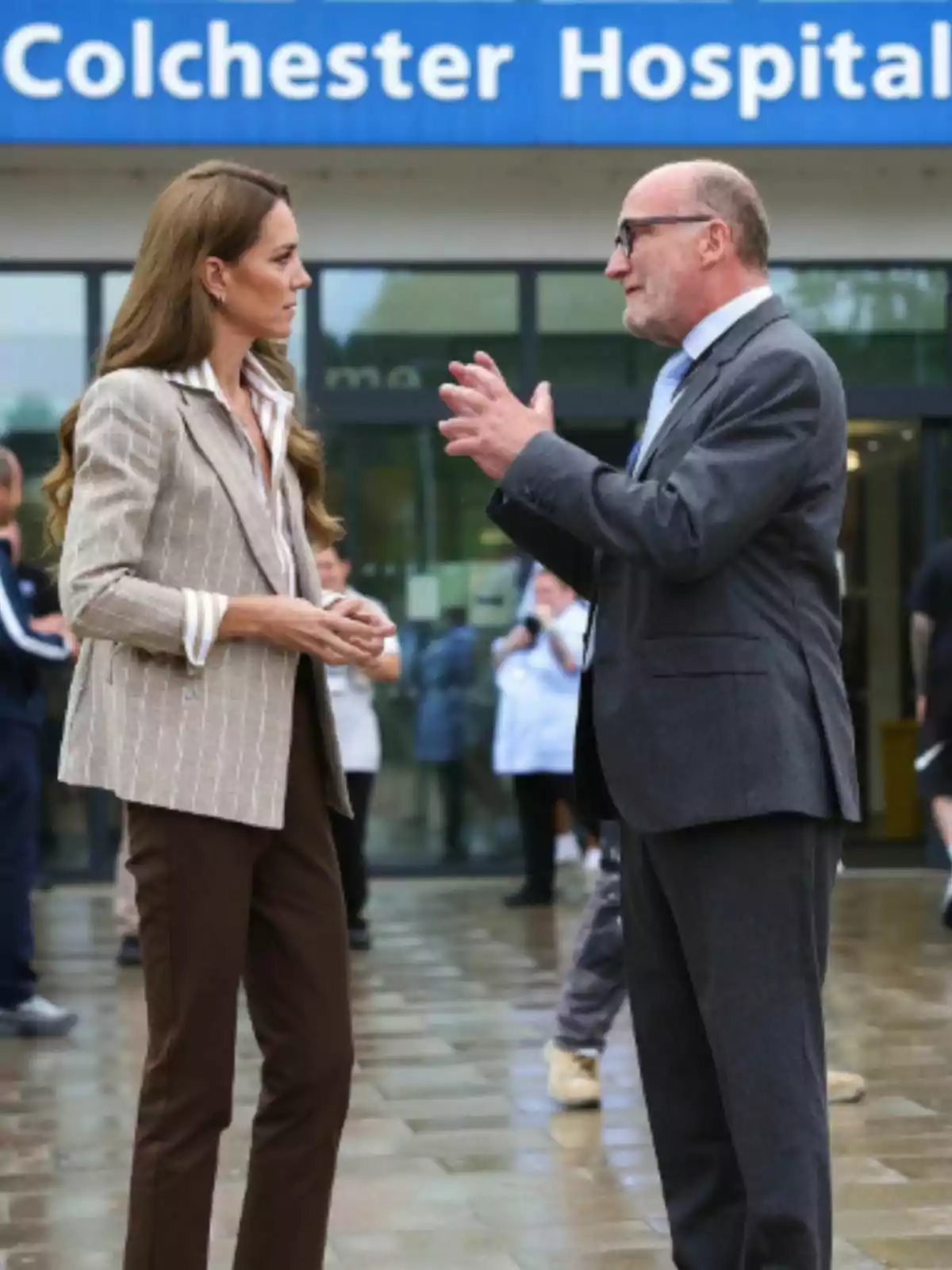 Kate Middleton i un home conversen davant l’entrada d’un hospital anomenat Colchester Hospital. Kate Middleton i un home conversen davant l’entrada d’un hospital anomenat Colchester Hospital.