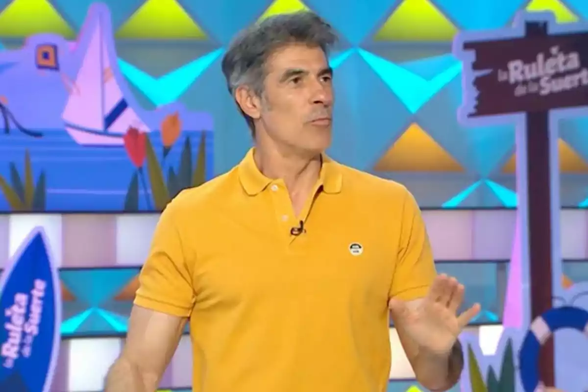 Jorge Fernández amb samarreta groga en un plató de televisió colorit amb un rètol de La Ruleta de la Suerte al fons Jorge Fernández amb samarreta groga en un plató de televisió colorit amb un rètol de La Ruleta de la Suerte al fons