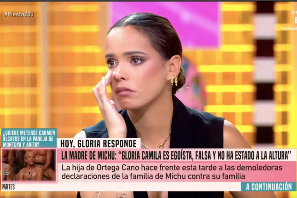 Gloria Camila con expresión seria y lágrimas en los ojos durante un programa de televisión con titulares y subtítulos en pantalla sobre un conflicto familiar Gloria Camila con expresión seria y lágrimas en los ojos durante un programa de televisión con titulares y subtítulos en pantalla sobre un conflicto familiar