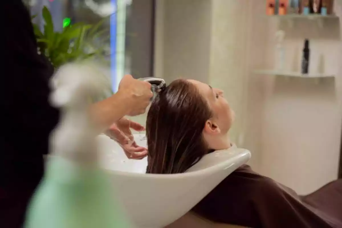 Persona recibiendo un lavado de cabello en una peluquería Persona recibiendo un lavado de cabello en una peluquería