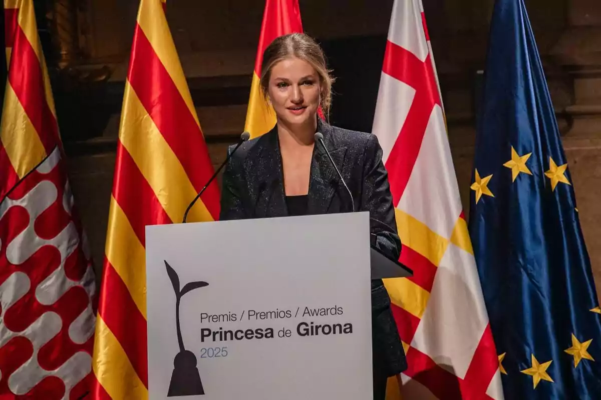 La princesa Leonor amb jaqueta fosca parla en un faristol durant la cerimònia dels Premis Princesa de Girona 2025 amb diverses banderes de fons. La princesa Leonor amb jaqueta fosca parla en un faristol durant la cerimònia dels Premis Princesa de Girona 2025 amb diverses banderes de fons.