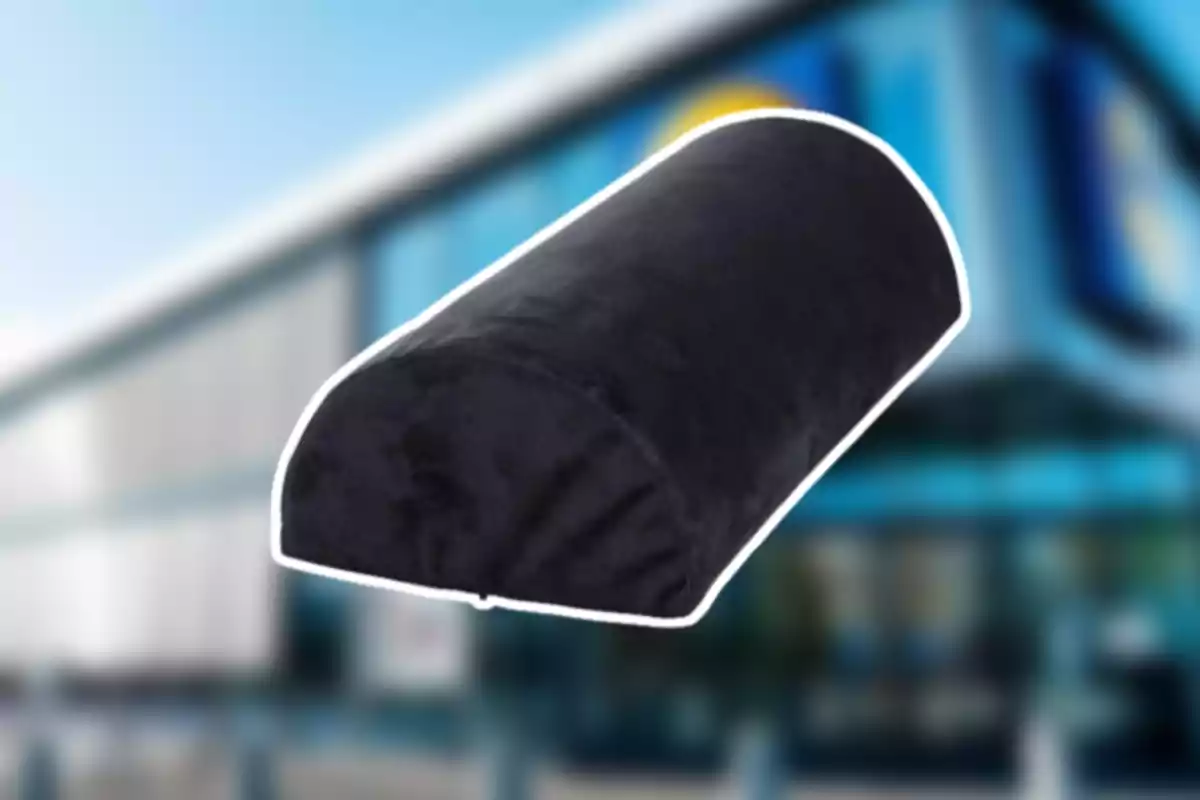 Coixí ortopèdic negre amb forma semicilíndrica sobre un fons d’edifici desenfocat Coixí ortopèdic negre amb forma semicilíndrica sobre un fons d’edifici desenfocat
