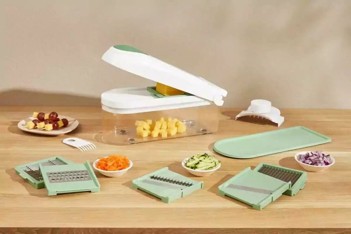 Tallador de verdures multifuncional amb diversos accessoris i plats petits amb aliments picats sobre una taula de fusta Tallador de verdures multifuncional amb diversos accessoris i plats petits amb aliments picats sobre una taula de fusta