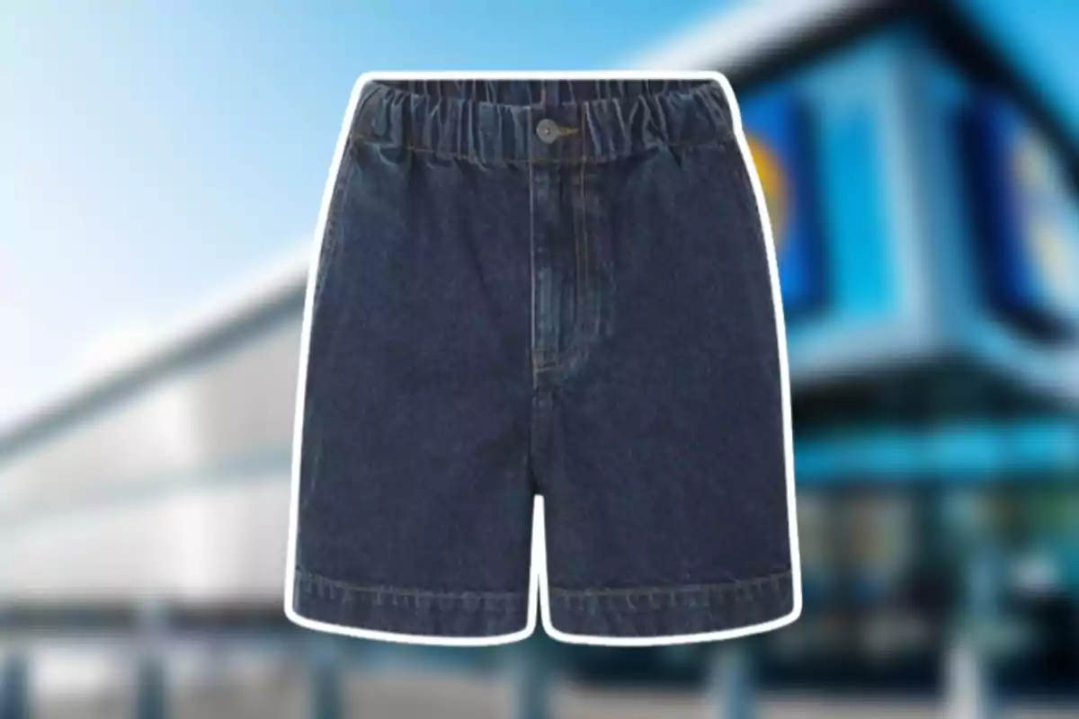 Shorts texans blaus amb goma a la cintura i botó al davant sobre un fons desenfocat d’un edifici modern