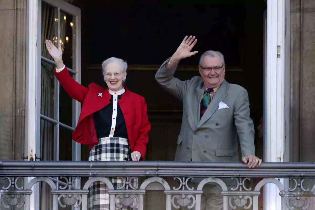 Margarita y Enrique de Dinamarca sonríen y saludan con la mano desde un balcón elegantemente decorado Margarita y Enrique de Dinamarca sonríen y saludan con la mano desde un balcón elegantemente decorado