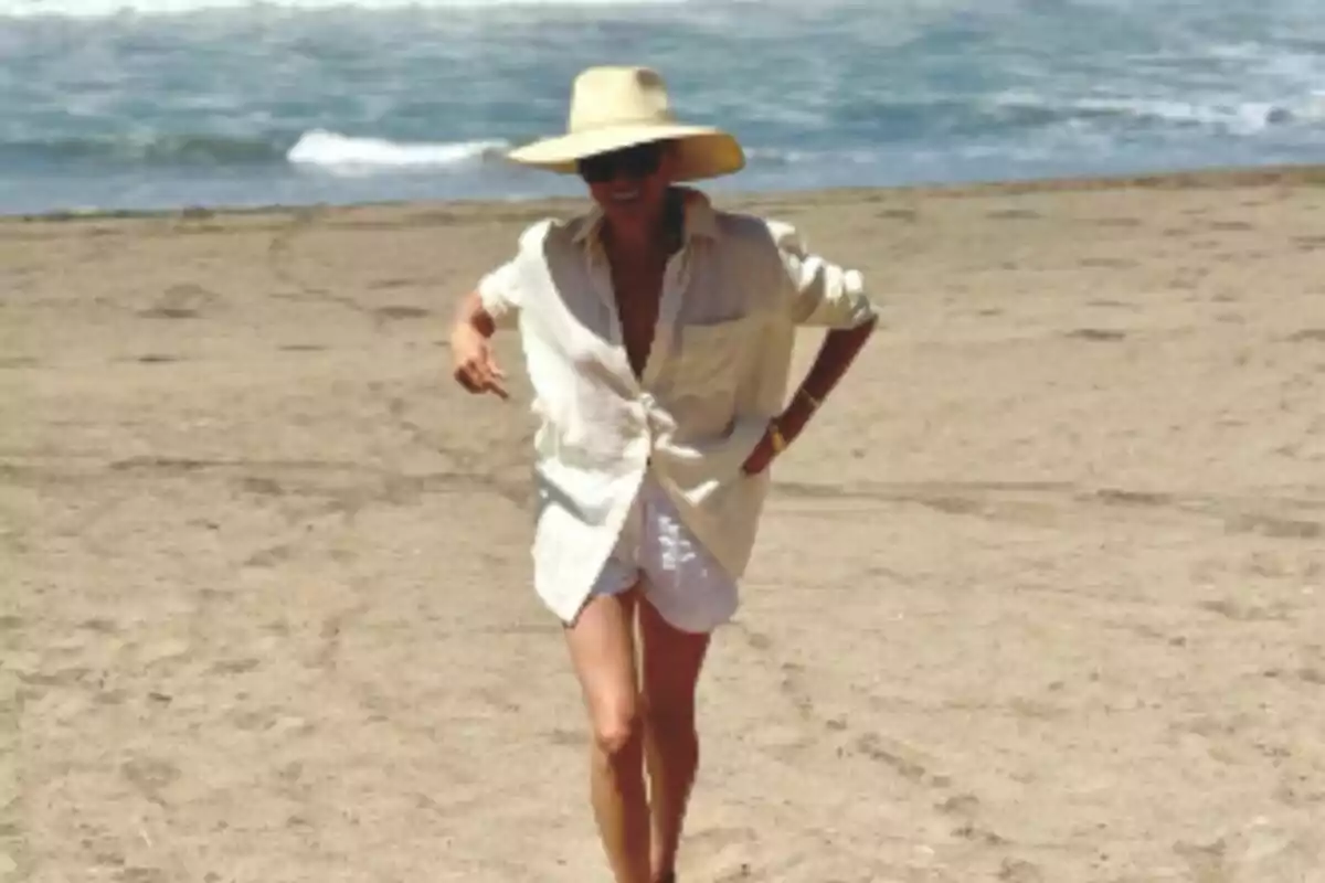 Meghan Markle amb un barret gran i ulleres de sol caminant per la platja amb el mar de fons. Meghan Markle amb un barret gran i ulleres de sol caminant per la platja amb el mar de fons.