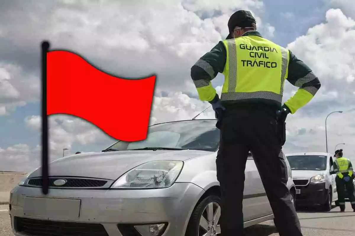 Agent de trànsit de la Guàrdia Civil detenint un cotxe platejat al costat d’una bandera vermella