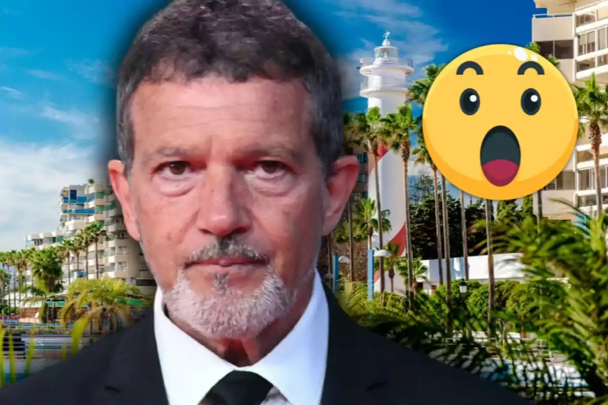 Antonio Banderas de cabello corto y barba canosa con expresión seria en primer plano, al fondo un paisaje urbano con palmeras y un faro, junto a un emoji de sorpresa