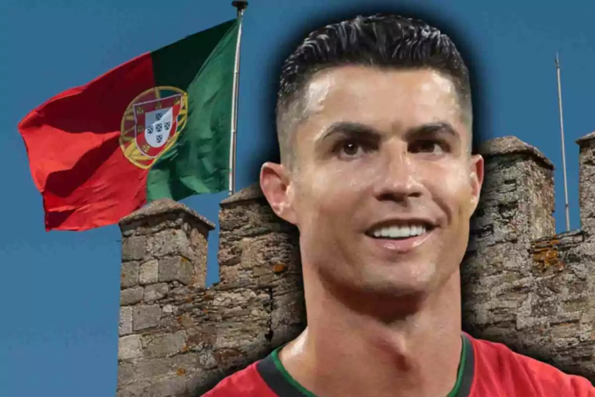 Cristiano Ronaldo somrient amb samarreta vermella davant d’una bandera de Portugal onejant i una muralla de pedra