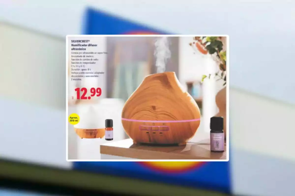 Humidificador difusor ultrasònic amb acabat de fusta sobre una taula al costat d’un flascó d’oli essencial i un preu de 12,99 euros Humidificador difusor ultrasònic amb acabat de fusta sobre una taula al costat d’un flascó d’oli essencial i un preu de 12,99 euros