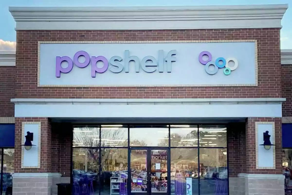 Façana d’una botiga anomenada popshelf amb un rètol en tons liles i blaus sobre una paret de maó vermell Façana d’una botiga anomenada popshelf amb un rètol en tons liles i blaus sobre una paret de maó vermell