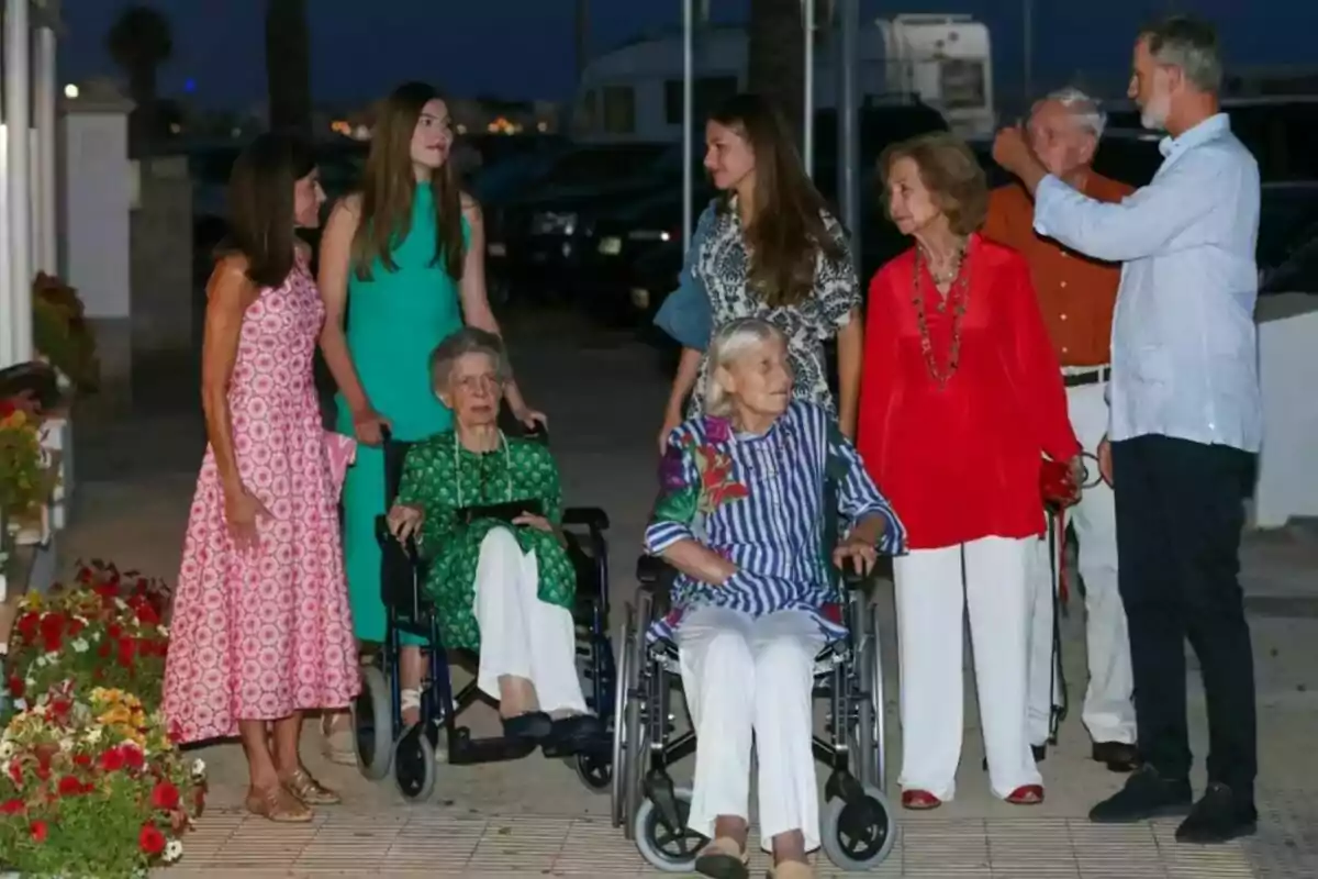 Un grupo de personas de diferentes edades, algunas en silla de ruedas, posan juntas al aire libre durante la noche, rodeadas de flores y con un ambiente relajado y familiar. Un grupo de personas de diferentes edades, algunas en silla de ruedas, posan juntas al aire libre durante la noche, rodeadas de flores y con un ambiente relajado y familiar.