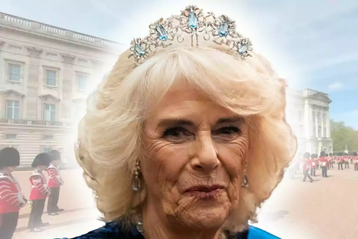 Dona de cabells rossos amb una corona de pedres blaves, que és la reina Camila Parker, davant del Palau de Buckingham i guàrdies amb uniforme vermell.
