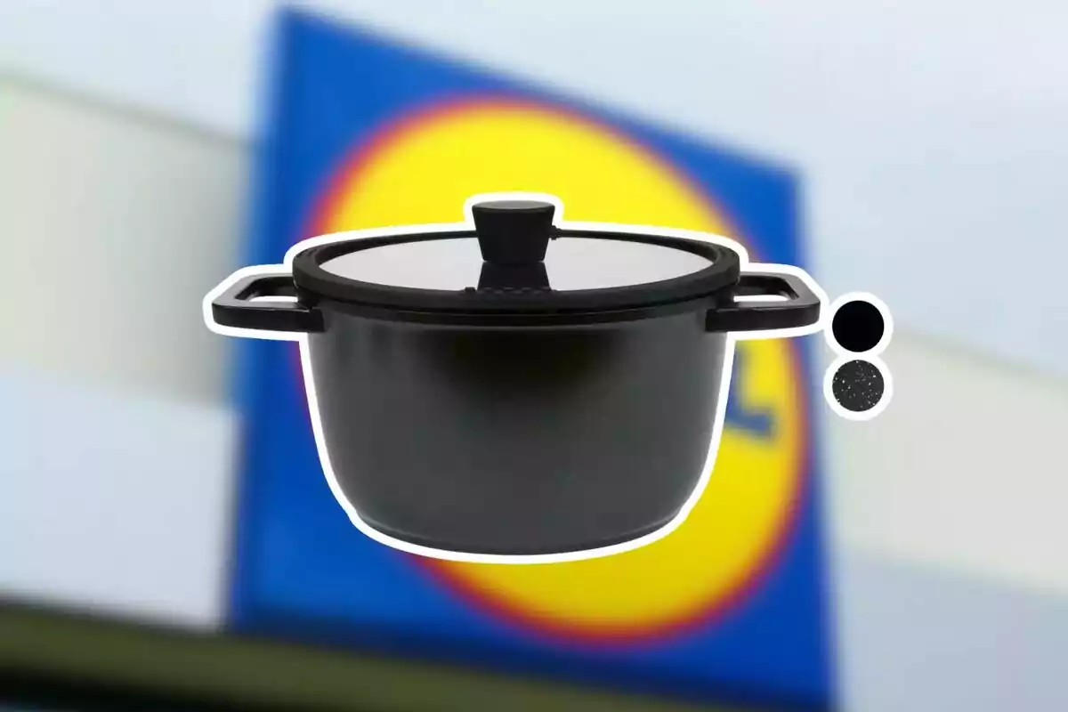 Olla negra amb tapa de vidre sobre un fons desenfocat d’un rètol de supermercat Olla negra amb tapa de vidre sobre un fons desenfocat d’un rètol de supermercat