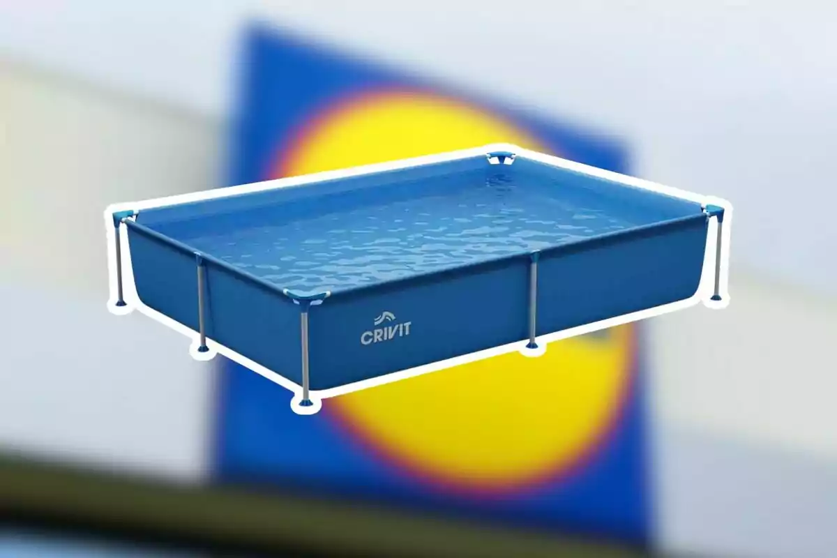 Piscina rectangular blava d’estructura metàl·lica amb aigua i el logotip Crivit al davant sobre un fons desenfocat de colors blau i groc