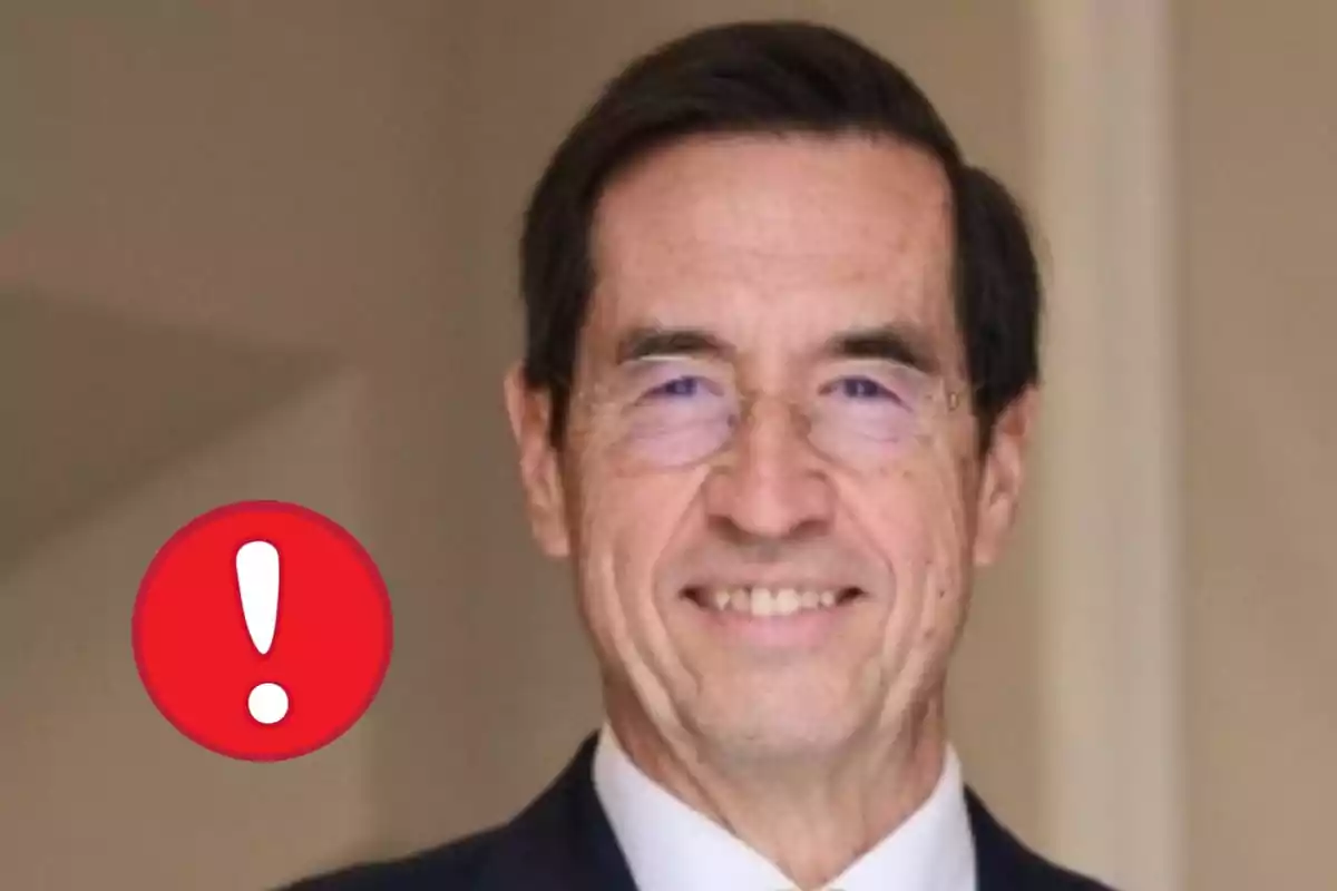 Mario Alonso Puig amb ulleres somrient i una icona d'advertència vermella amb un signe d'exclamació a l'esquerra