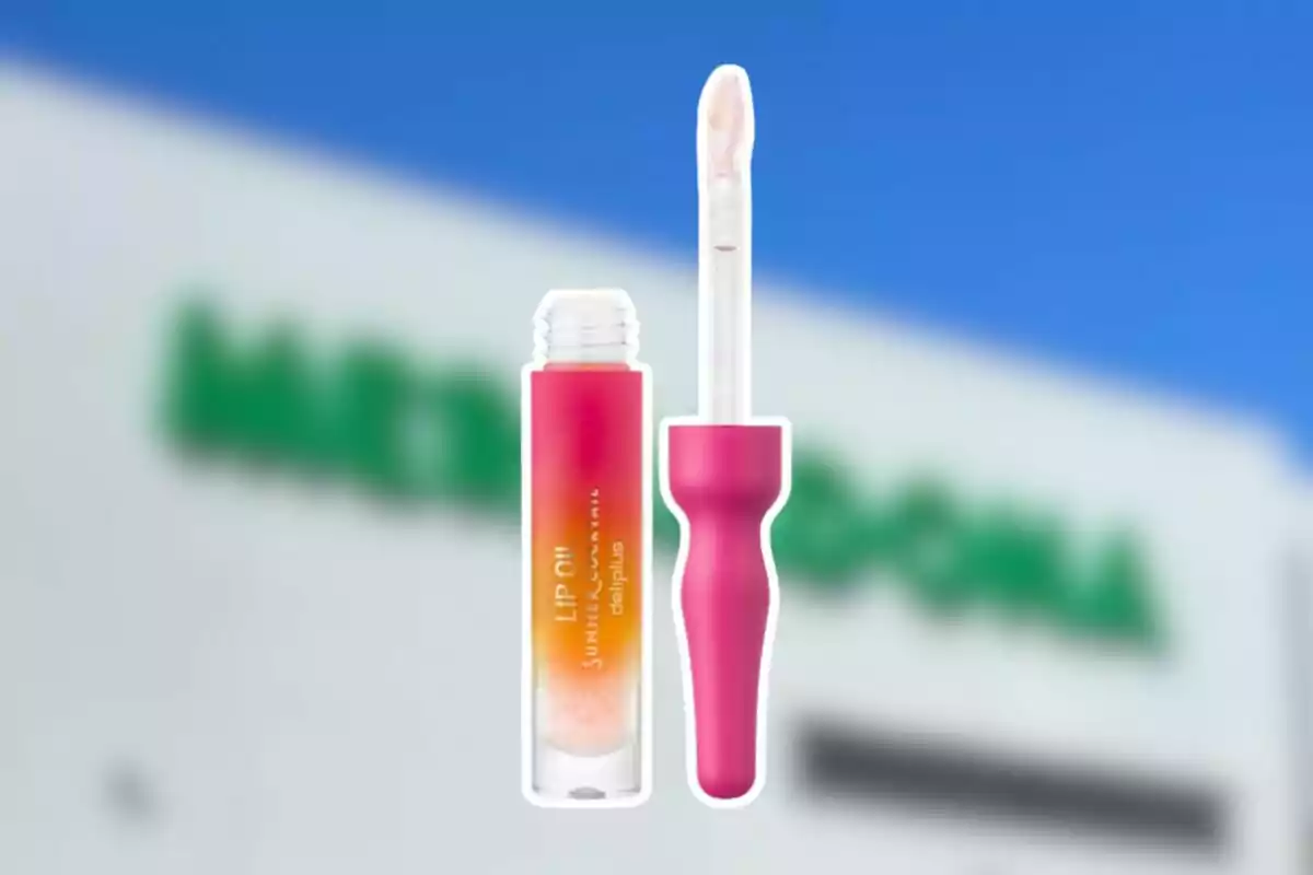 Un brillant de llavis amb aplicador rosa i envàs degradat en tons taronja i rosa sobre un fons desenfocat d’una botiga Un brillant de llavis amb aplicador rosa i envàs degradat en tons taronja i rosa sobre un fons desenfocat d’una botiga