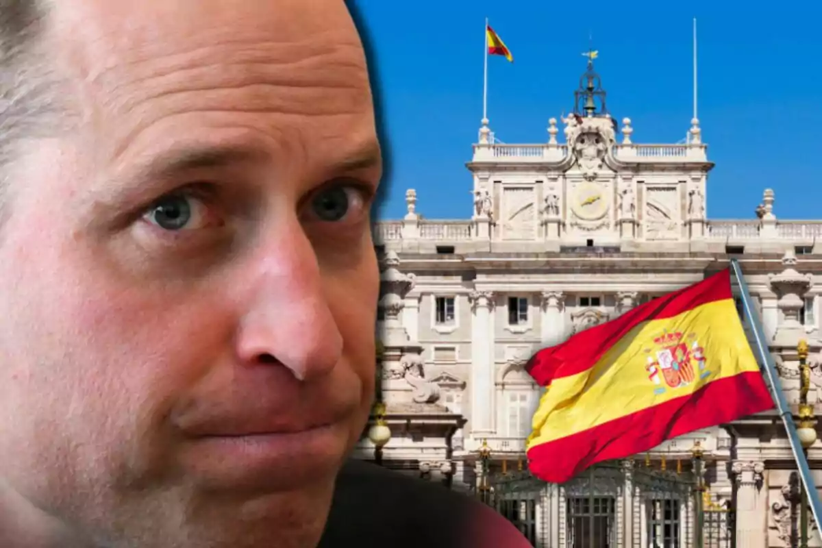 Primer pla del príncep Guillem amb expressió seriosa davant d’un edifici històric i una bandera d’Espanya onejant