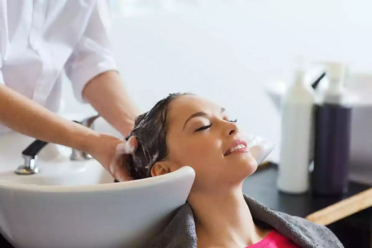 Mujer disfrutando mientras le lavan el cabello en una peluquería Mujer disfrutando mientras le lavan el cabello en una peluquería