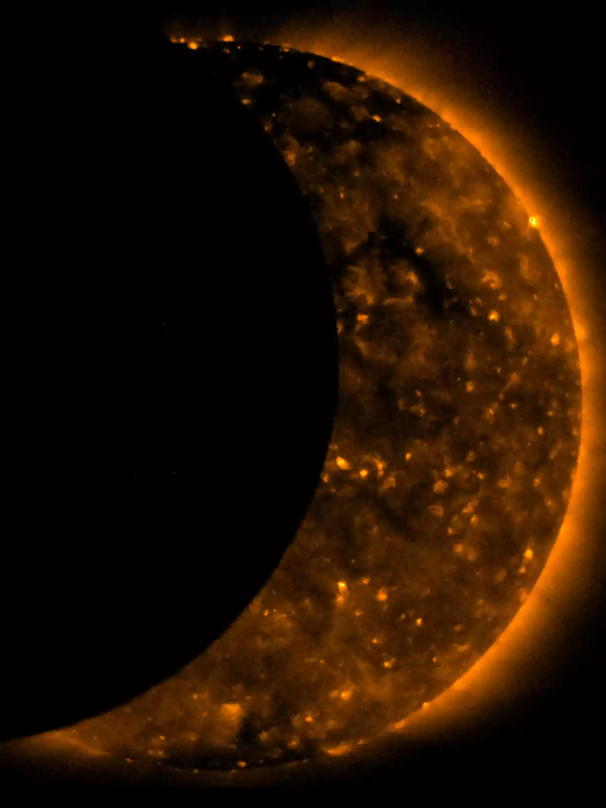 La imagen muestra un eclipse solar donde la Luna cubre parcialmente al Sol, que brilla con un resplandor anaranjado intenso. La imagen muestra un eclipse solar donde la Luna cubre parcialmente al Sol, que brilla con un resplandor anaranjado intenso.