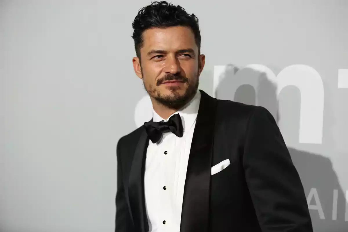 Orlando Bloom amb esmòquing negre i llacet posant davant d’un fons gris en un esdeveniment formal Orlando Bloom amb esmòquing negre i llacet posant davant d’un fons gris en un esdeveniment formal
