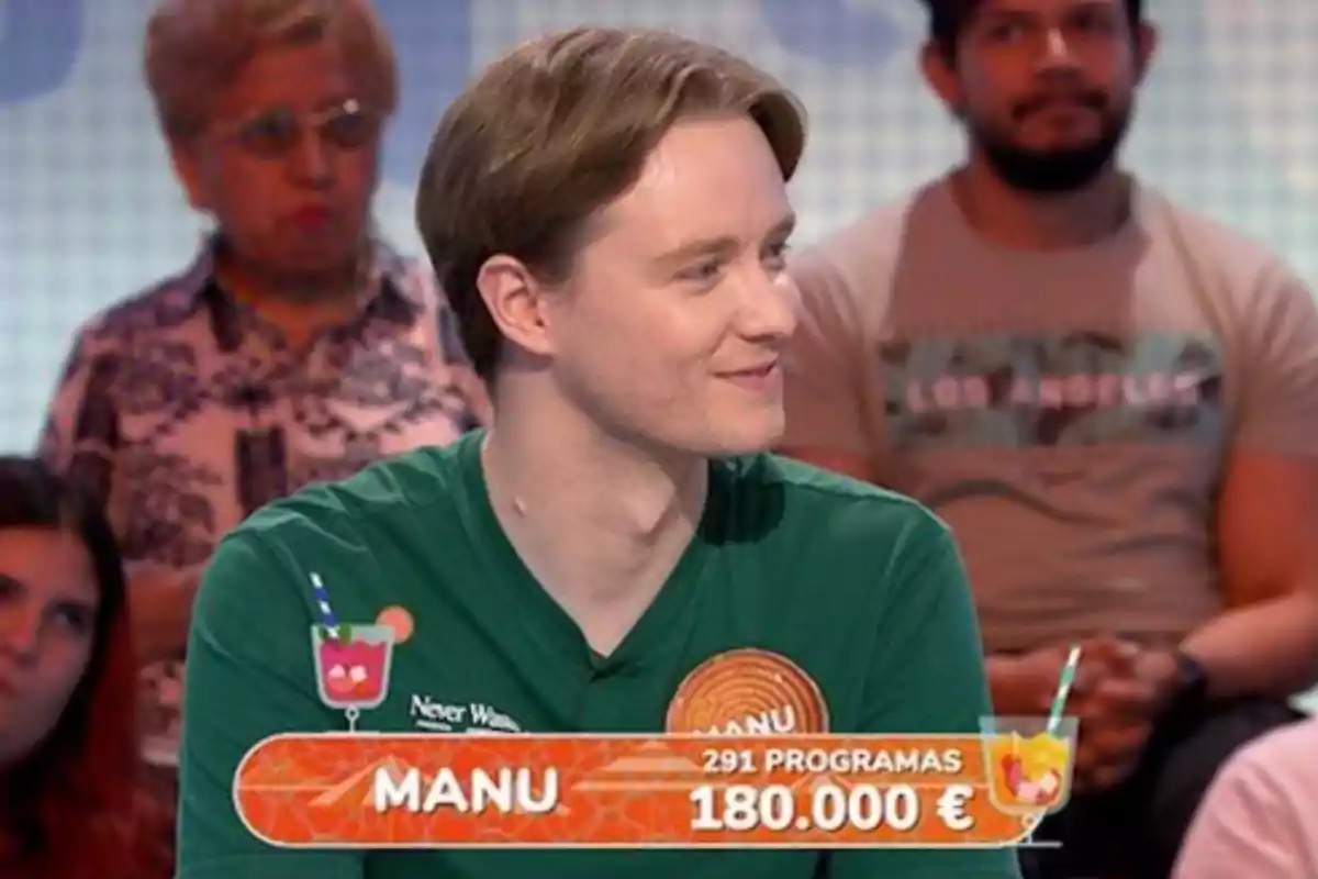Manu amb una samarreta verda somriu en un programa de concursos, amb un rètol que mostra el seu nom, el nombre de programes en què ha participat i la quantitat de diners guanyada, mentre el públic observa al fons. Captura de 'Pasapalabra' Manu amb una samarreta verda somriu en un programa de concursos, amb un rètol que mostra el seu nom, el nombre de programes en què ha participat i la quantitat de diners guanyada, mentre el públic observa al fons. Captura de 'Pasapalabra'