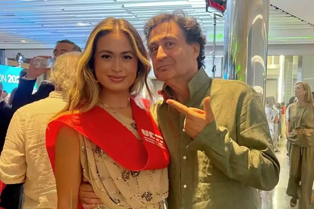Una jove, que és María Rodríguez, amb una banda vermella de graduació somriu al costat de Pepe Rodríguez, que l’assenyala mentre posen en un esdeveniment a l’interior envoltats d’altres persones. Una jove, que és María Rodríguez, amb una banda vermella de graduació somriu al costat de Pepe Rodríguez, que l’assenyala mentre posen en un esdeveniment a l’interior envoltats d’altres persones.
