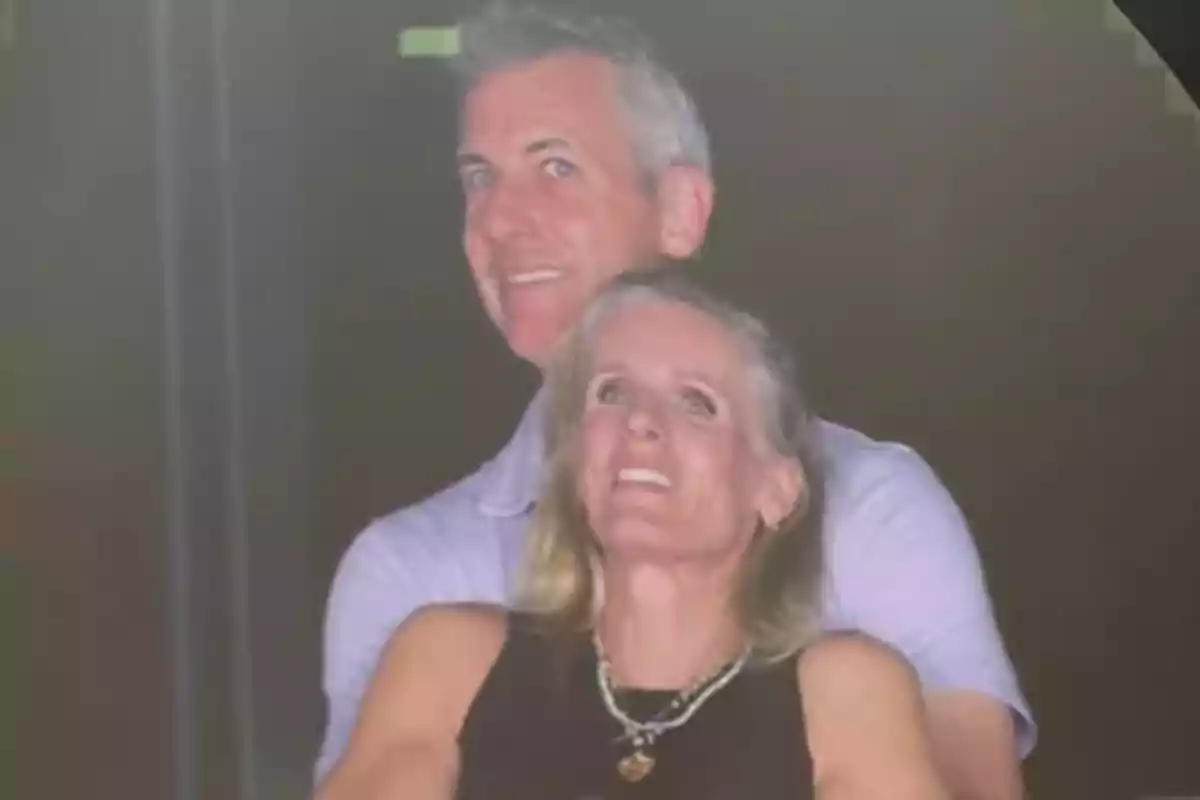 Andy Byron i una dona somriu abraçada mentre mira cap amunt en un ambient fosc Andy Byron i una dona somriu abraçada mentre mira cap amunt en un ambient fosc