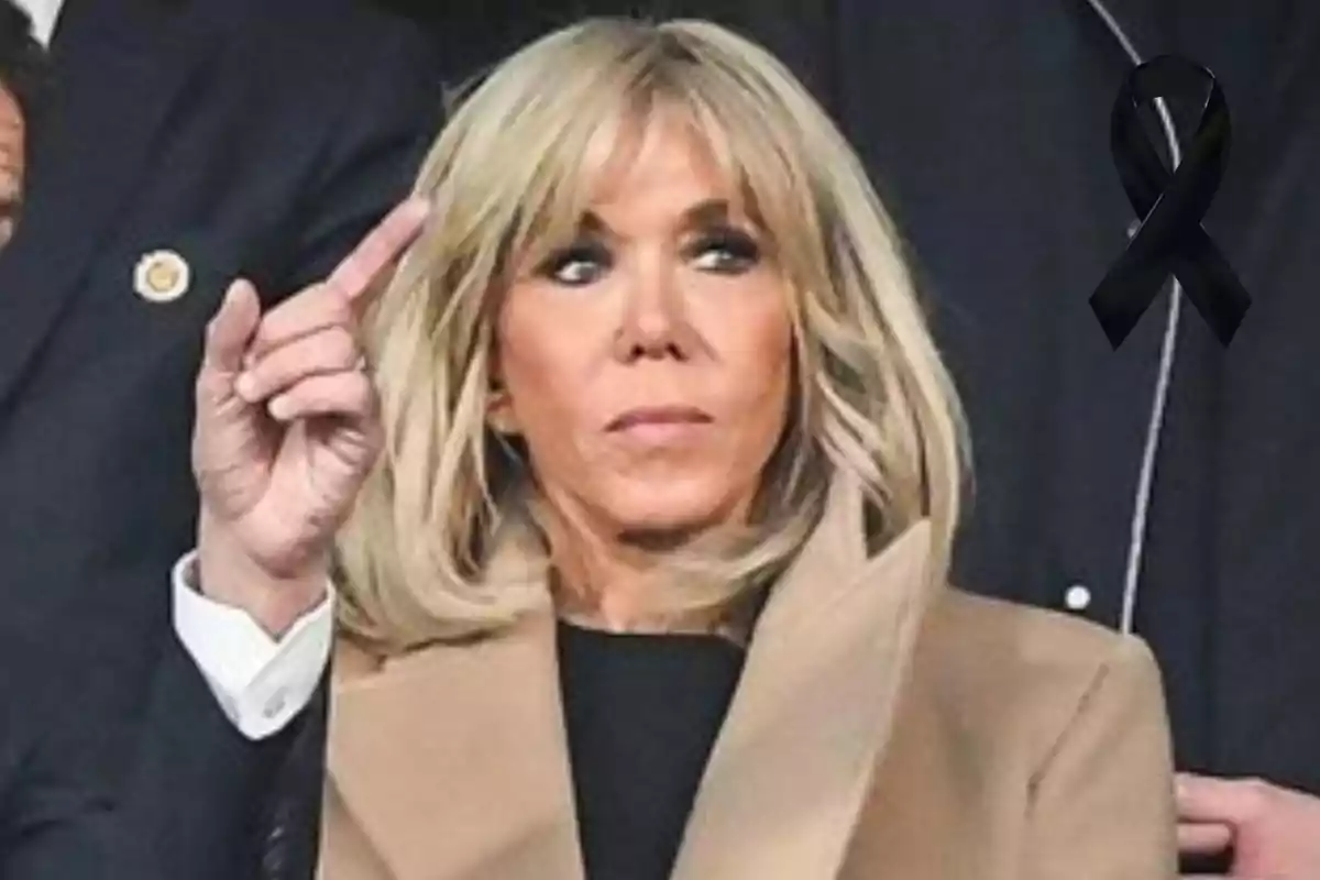 Mujer rubia con expresión seria levantando la mano y un moño negro de luto en la esquina superior derecha Mujer rubia con expresión seria levantando la mano y un moño negro de luto en la esquina superior derecha