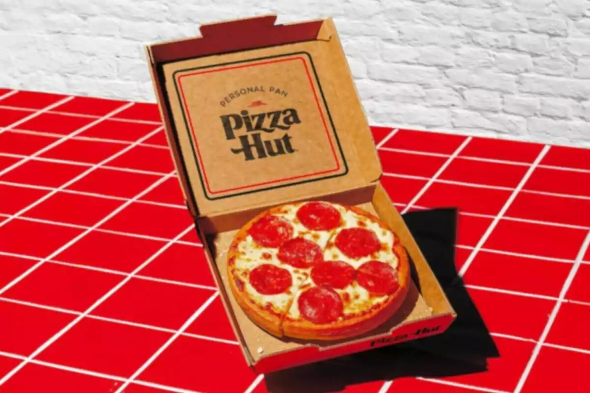 Pepperoni pizza in a Pizza Hut box on a red checkered surface Pepperoni pizza in a Pizza Hut box on a red checkered surface