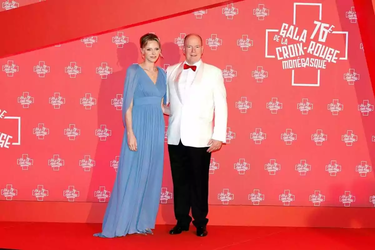 Charlene y Alberto de Mónaco elegantemente vestida posa sobre una alfombra roja frente a un fondo con logotipos de la Gala de la Cruz Roja Monegasca Charlene y Alberto de Mónaco elegantemente vestida posa sobre una alfombra roja frente a un fondo con logotipos de la Gala de la Cruz Roja Monegasca