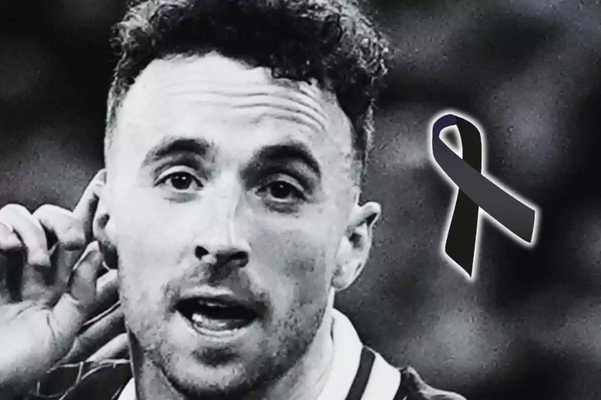 Black and white photograph of Diogo Jota with a serious expression and a black mourning ribbon on one side.