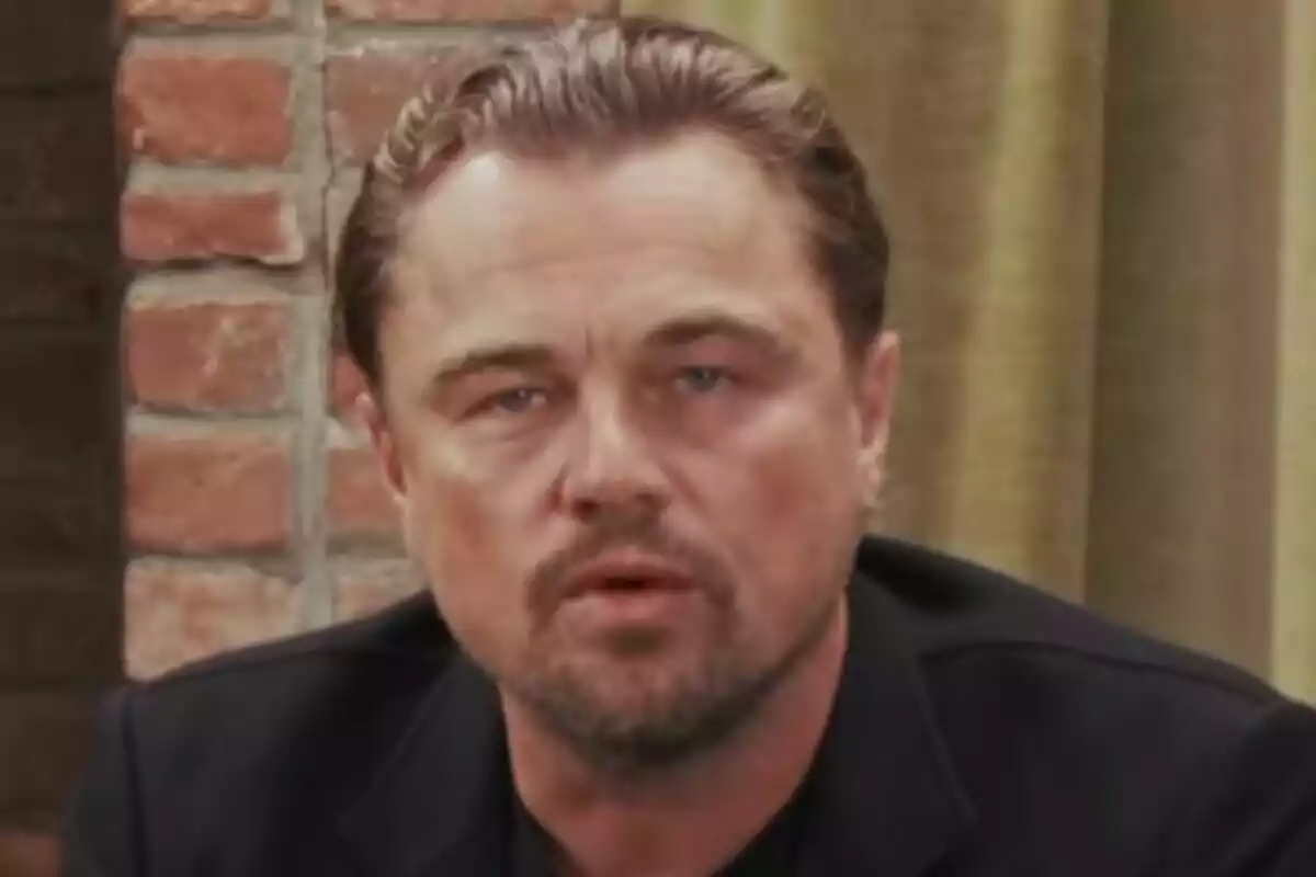 Primer plano de Leonardo di Caprio con expresión seria, fondo de pared de ladrillos y cortina verde. Primer plano de Leonardo di Caprio con expresión seria, fondo de pared de ladrillos y cortina verde.