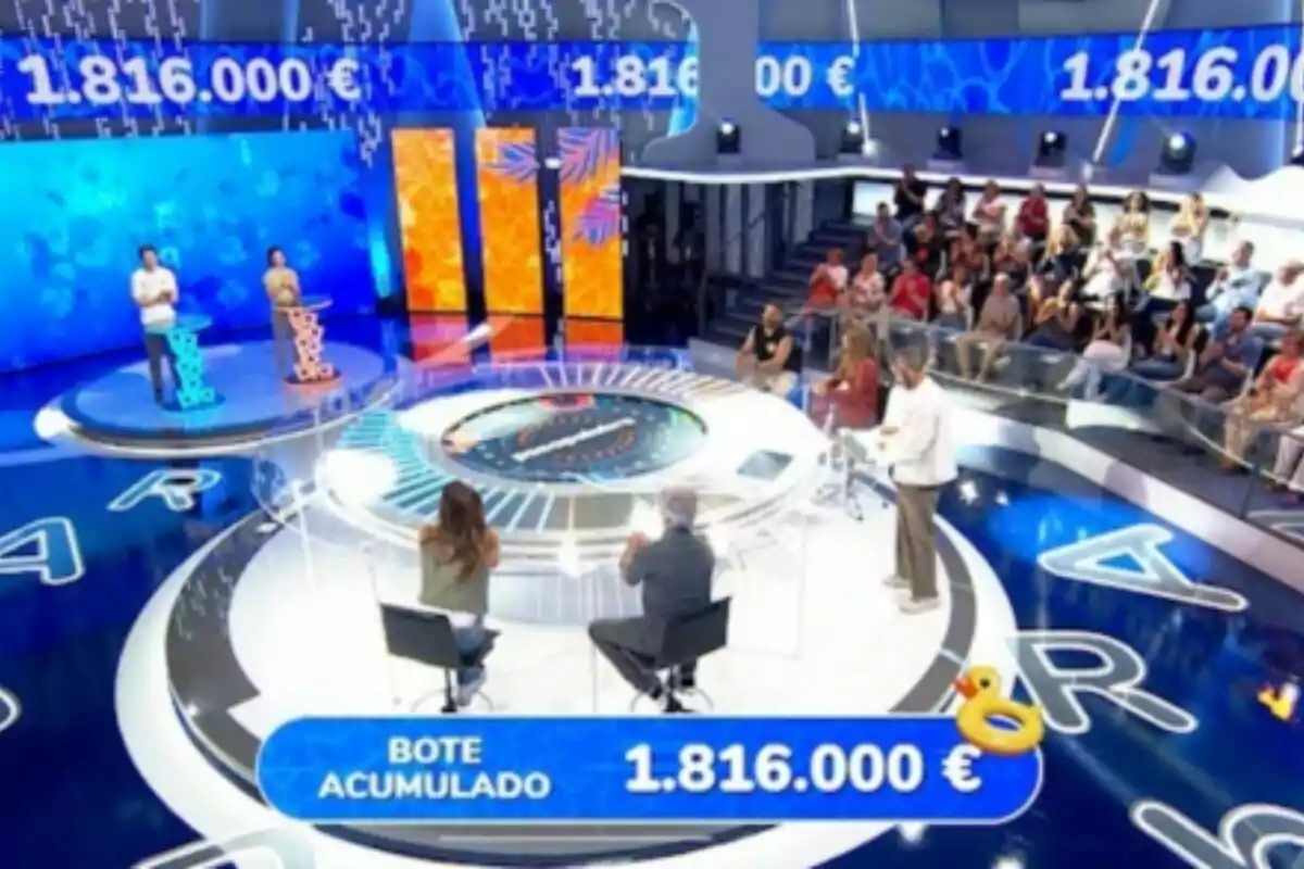 'Pasapalabra', el concurs televisiu amb dos concursants drets, un presentador, dues persones assegudes i públic al fons, amb un premi acumulat d’un milió vuit-cents setze mil euros mostrat a la pantalla. 'Pasapalabra', el concurs televisiu amb dos concursants drets, un presentador, dues persones assegudes i públic al fons, amb un premi acumulat d’un milió vuit-cents setze mil euros mostrat a la pantalla.