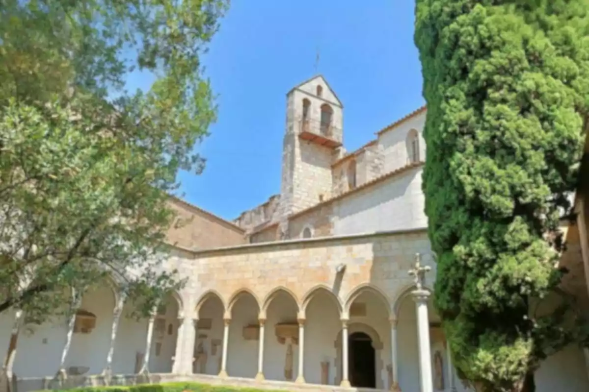 Claustre d’un antic monestir envoltat d’arbres i vegetació sota un cel serè Claustre d’un antic monestir envoltat d’arbres i vegetació sota un cel serè