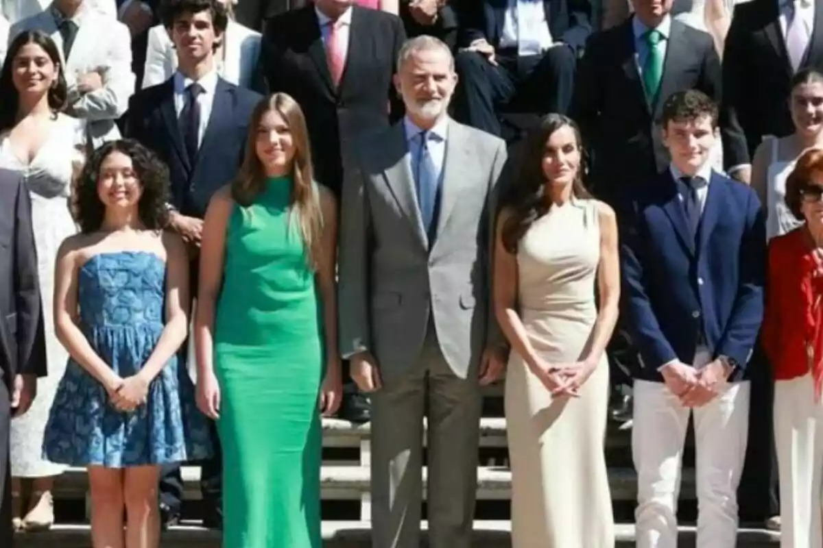 Un grupo de personas elegantemente vestidas posa para una foto al aire libre en una escalera, que son los reyes de España junto a la infanta Sofía. Un grupo de personas elegantemente vestidas posa para una foto al aire libre en una escalera, que son los reyes de España junto a la infanta Sofía.