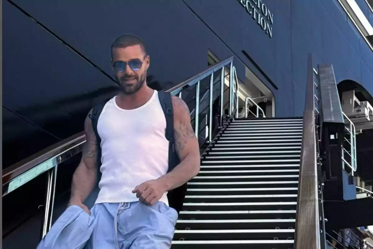 Ricky Martin wearing sunglasses and a white t-jersey walking down metal stairs next to a modern building. Ricky Martin wearing sunglasses and a white t-jersey walking down metal stairs next to a modern building.