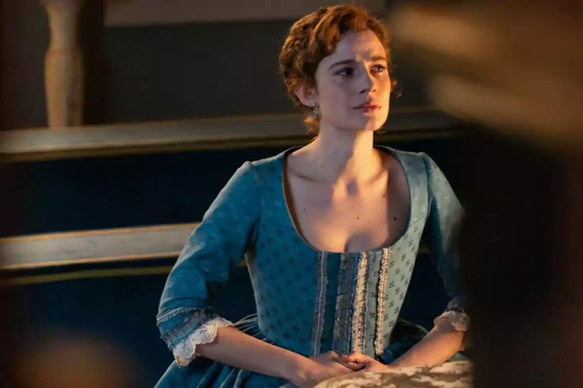 Rocío Suárez de Puga, embarassada, amb expressió seriosa vestida amb un vestit blau d’època asseguda en un banc antic. Rocío Suárez de Puga, embarassada, amb expressió seriosa vestida amb un vestit blau d’època asseguda en un banc antic.