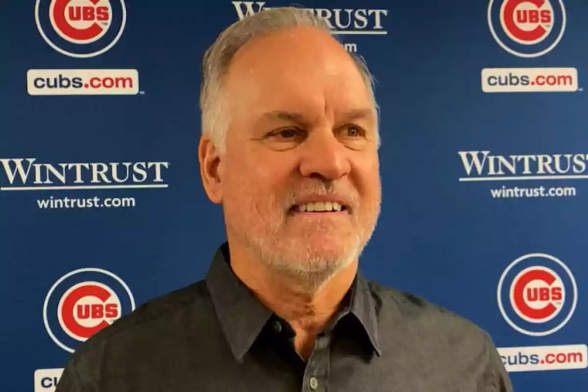 Ryne Sandberg sonriendo frente a un fondo azul con logotipos de los Chicago Cubs y Wintrust Ryne Sandberg sonriendo frente a un fondo azul con logotipos de los Chicago Cubs y Wintrust