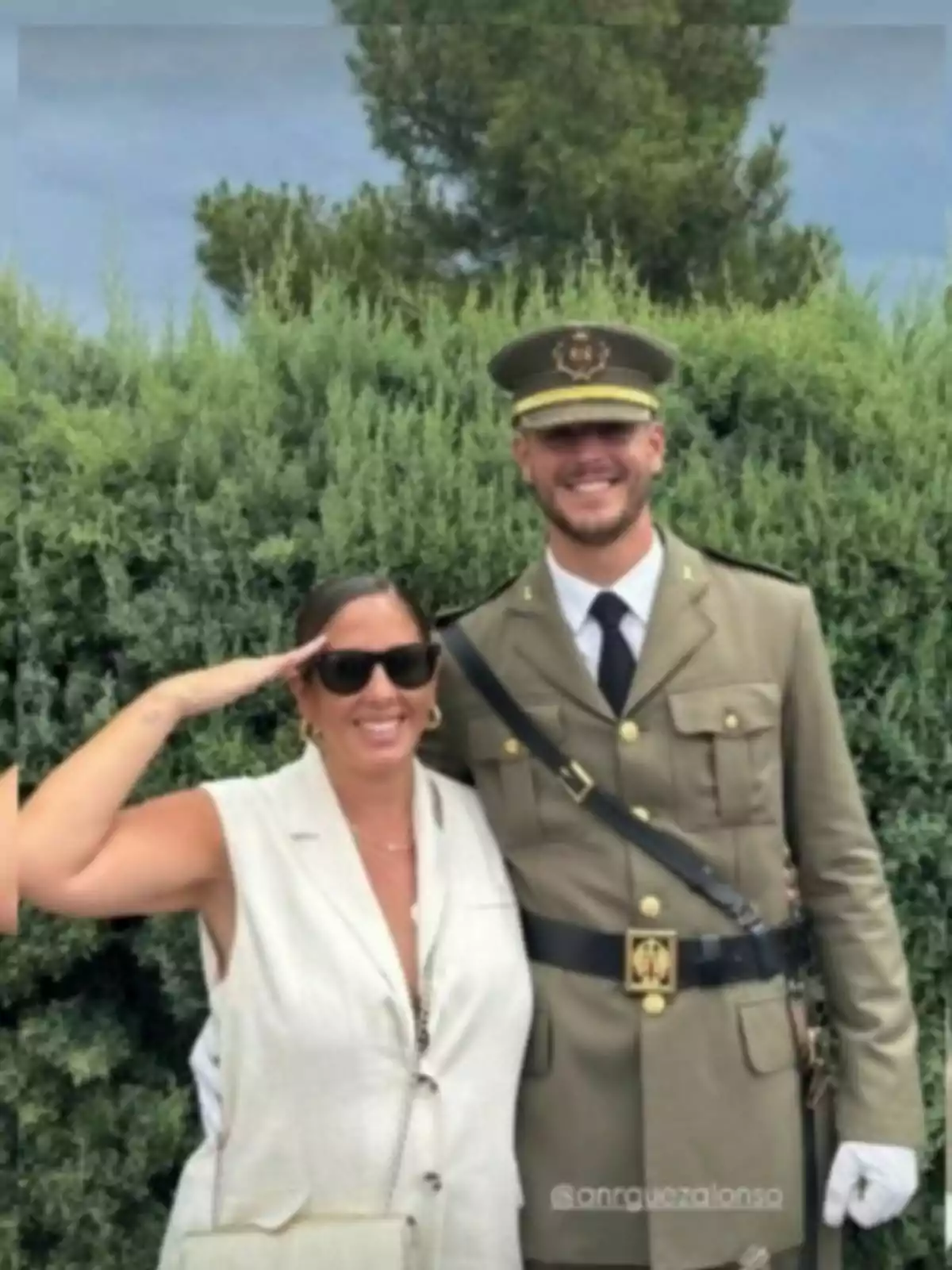Anabel Pantoja, con gafas de sol y llevándose una mano a la frente, posa con su cuñado, con uniforme militar frente a un fondo de arbustos verdes Anabel Pantoja, con gafas de sol y llevándose una mano a la frente, posa con su cuñado, con uniforme militar frente a un fondo de arbustos verdes