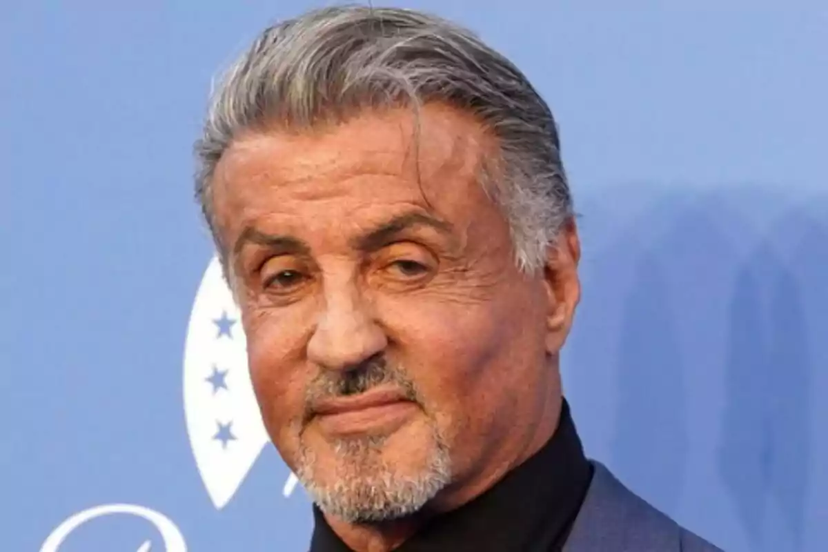 Close-up of Sylvester Stallone with a serious expression posing in front of a blue background. Close-up of Sylvester Stallone with a serious expression posing in front of a blue background.