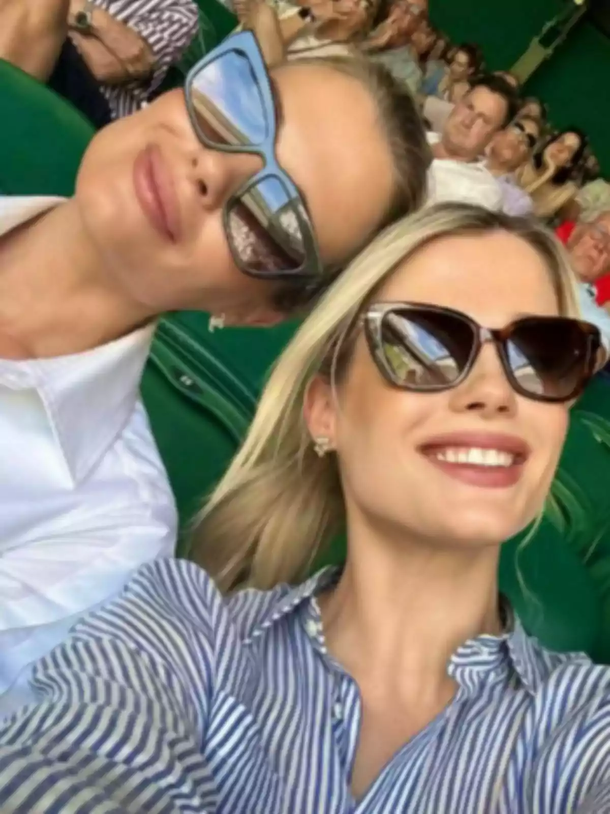Dues dones somriuen amb ulleres de sol, una d'elles és l'Amelia Spencer Mallett, mentre es fan una selfie en un estadi ple de gent. Dues dones somriuen amb ulleres de sol, una d'elles és l'Amelia Spencer Mallett, mentre es fan una selfie en un estadi ple de gent.