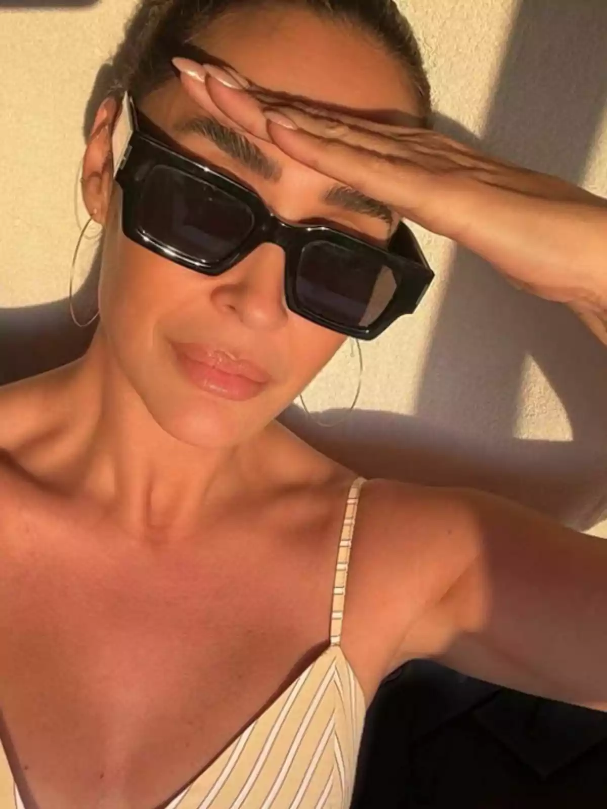 Vicky Martín Berrocal con gafas de sol oscuras y vestido de tirantes claros se cubre los ojos con la mano mientras disfruta de la luz del sol. Vicky Martín Berrocal con gafas de sol oscuras y vestido de tirantes claros se cubre los ojos con la mano mientras disfruta de la luz del sol.