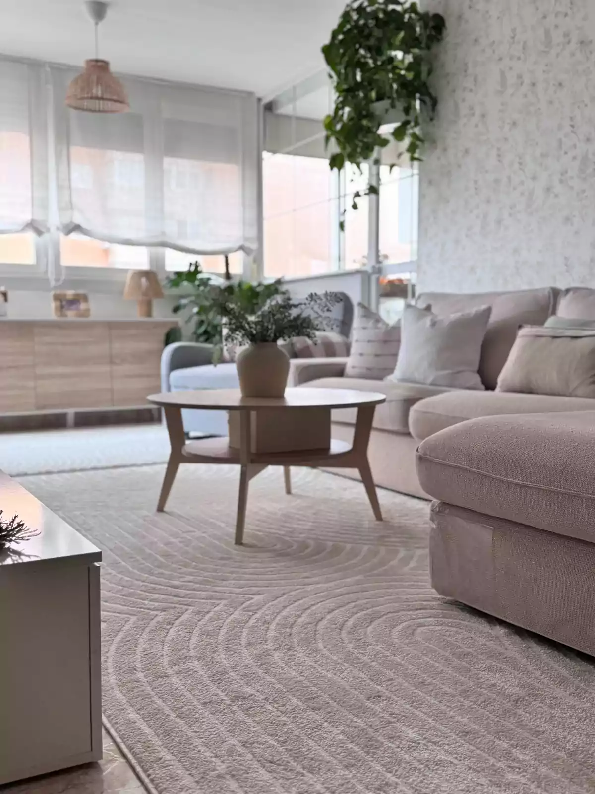 Sala luminosa decorada en tonos neutros con sofá beige, mesa de centro de madera, alfombra clara con textura y plantas decorativas Sala luminosa decorada en tonos neutros con sofá beige, mesa de centro de madera, alfombra clara con textura y plantas decorativas