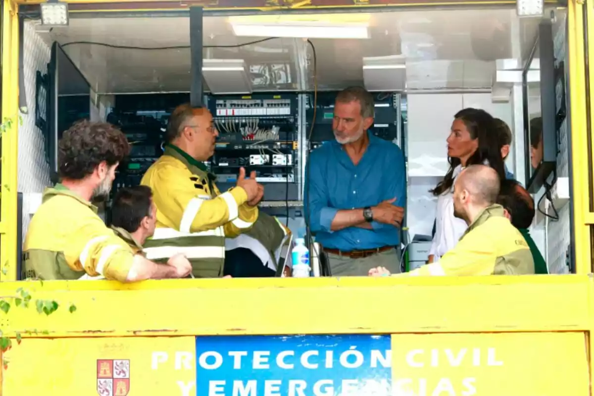 Diverses persones conversen dins d’una unitat mòbil de protecció civil i emergències, algunes porten uniformes grocs i d’altres roba de carrer, envoltades d’equips electrònics. Diverses persones conversen dins d’una unitat mòbil de protecció civil i emergències, algunes porten uniformes grocs i d’altres roba de carrer, envoltades d’equips electrònics.